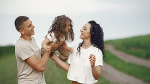 A joyful family moment outdoors with parents playing with their daughter.